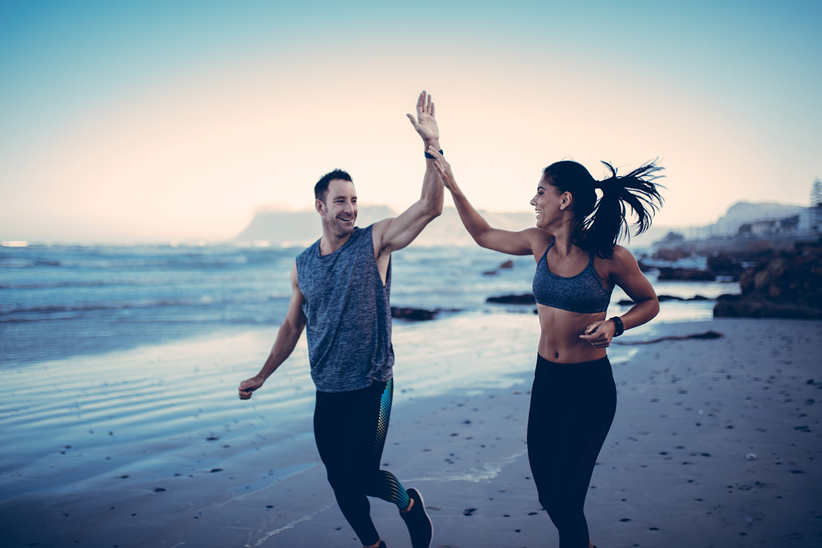 Fitness Couple giving each other high five after hard training session on the beach